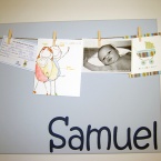 peg board A pale blue board with cards and a photo pegged to it and the name Samuel on it