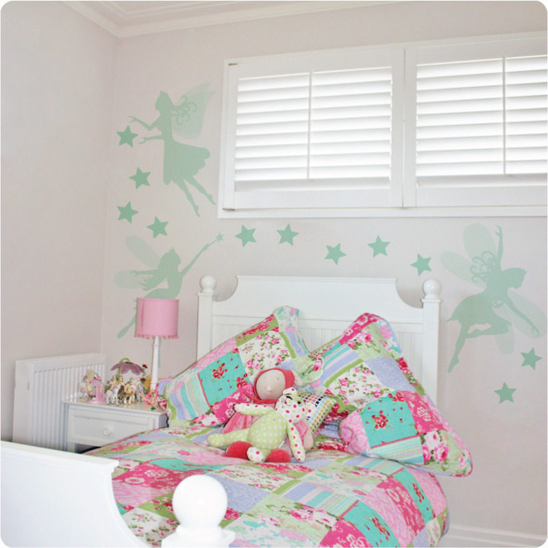Pretty fairies removable wall stickers in mint behind a white bed and white side table