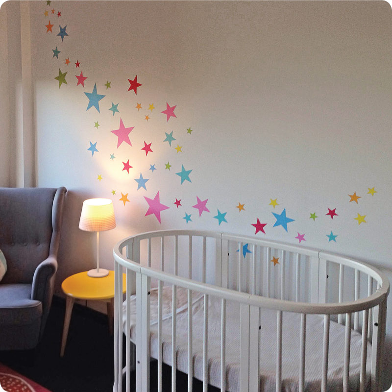 Stars removable wall stickers for childrens rooms behind the crib and round table with lamp shade on top