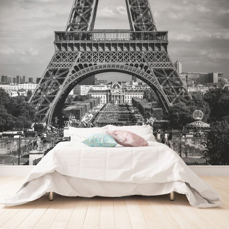 A black and white image of the Eiffel Tower on a wall behind a bed with cushions