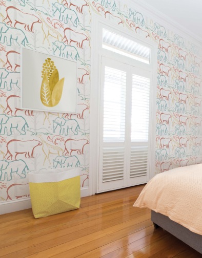 A bedroom with a yellow print framed and animals wallpaper on the wall