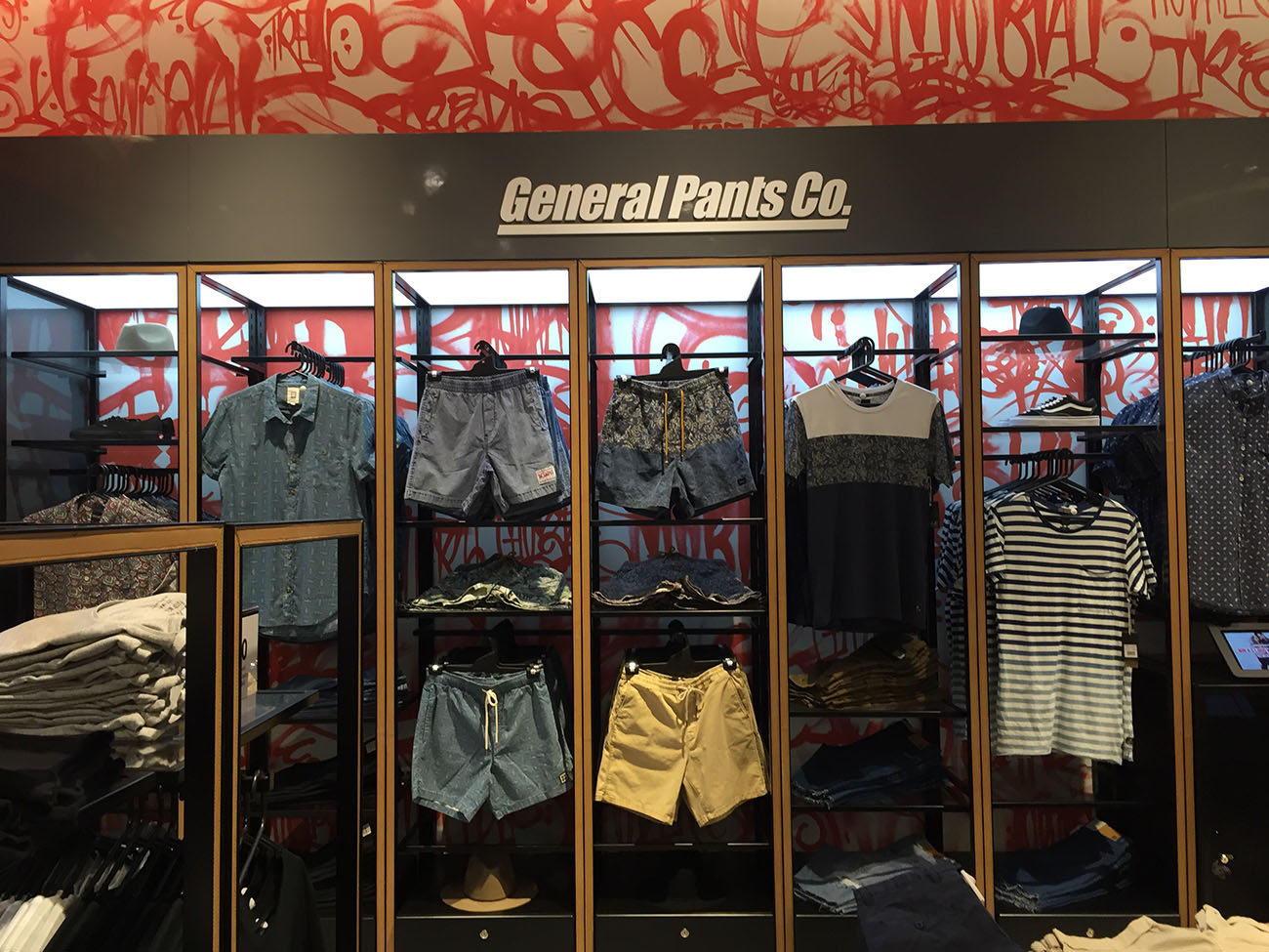 Clothes in a store with graffiti wall behind